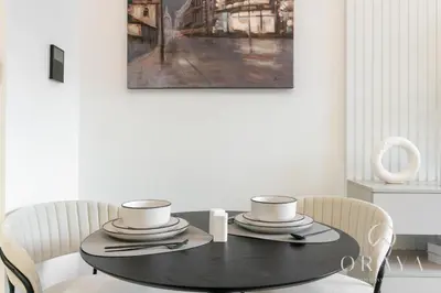 a black dining room table with two chairs and a painting at Oraya - Studio With Jaw-Dropping Canal and Burj Views - Business bay in Dubai