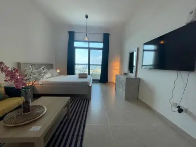 a large living room with a bed and a tv at Studio in Silicon Oasis in Dubai