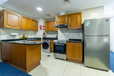 a kitchen with wooden cabinets and a stainless steel refrigerator at Havana Holiday Homes Oud Metha in Dubai