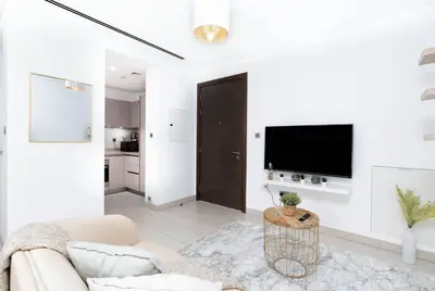 a white living room with a couch and a tv at Serenity Studio in Dubai