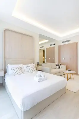 a white bedroom with a large bed and a couch at Modern Stu Near Downtown Dubai Pool Gym WiFi in Dubai