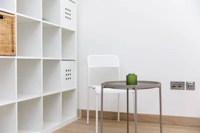 a table and a chair in a room with shelves at Spacious Minimalistic Studio in Dubai