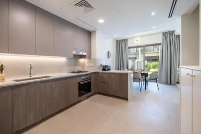a kitchen with wooden cabinets and a dining room at Exclusive Spacious Villa I Garden I Tilal Al Ghaf in Dubai