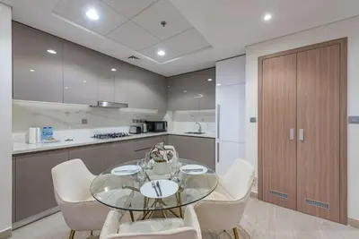 a kitchen with a glass table and white chairs at Modern 1BR at Farhad Azizi Al Jaddaf - Sleeps 4 in Dubai