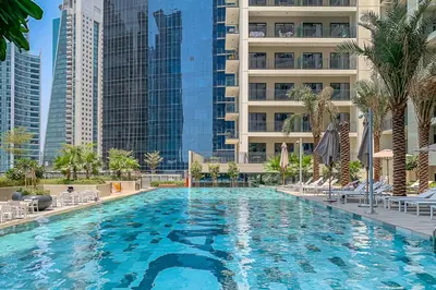 a large swimming pool with palm trees and buildings at Frank Porter - Zada Tower in Dubai