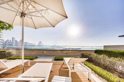 a patio with white chairs and an umbrella at Emaar Beachfront - Beach Vista Tower, Dubai Marina in Dubai