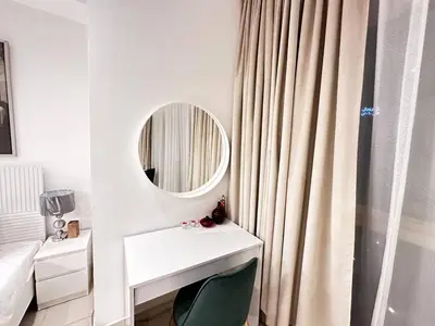 a white bathroom with a mirror and a green chair at Lovely Newly Furnished Ocean View Studio in Royal Oceanic Tower in Dubai