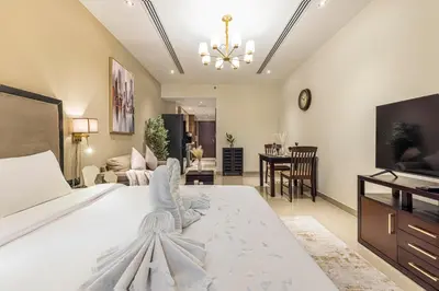 a bedroom with a large white bed and a living room at Daniels Cityscape Studio at Elite Downtown in Dubai