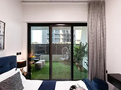 a bedroom with a bed and a sliding glass door at Trophy Lux Suite With Garden Balcony and Burj Khalifa Views in Dubai