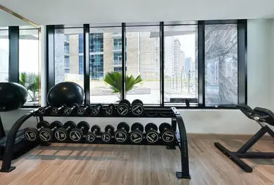 a gym with a bench and exercise equipment in front of a window at Trophy Lux Suite With Garden Balcony and Burj Khalifa Views in Dubai