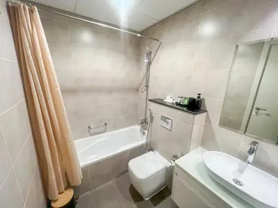 a bathroom with a toilet and a tub and a sink at Modern Condo With Wide City Views From Balcony in Dubai