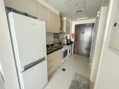 a white kitchen with a refrigerator and a stove at Modern Condo With Wide City Views From Balcony in Dubai