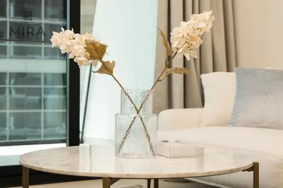 a vase with flowers on a table in a living room at Mira Holiday Homes - Serviced 1 bedroom with canal view in Dubai