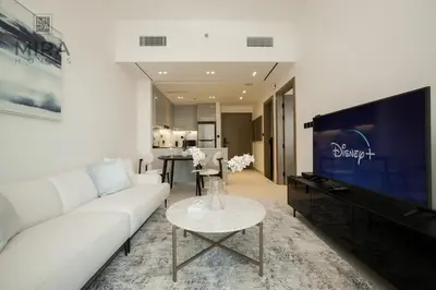 a living room with a white couch and a tv at Mira Holiday Homes - Serviced 1 bedroom with canal view in Dubai