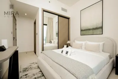 a bedroom with a large white bed and a desk at Mira Holiday Homes - Serviced 1 bedroom with canal view in Dubai