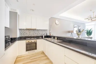 a kitchen with white cabinets and black counter tops at Daniels Burj Khalifa View 2BR at Paramount Midtown in Dubai