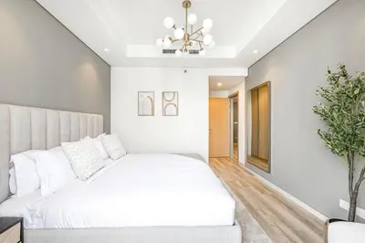 a bedroom with a white bed and a chandelier at Daniels Burj Khalifa View 2BR at Paramount Midtown in Dubai
