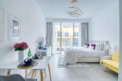 a white bedroom with a bed and a living room at The Smart Concierge - Luma 21 in Dubai