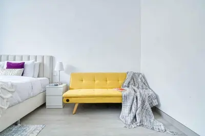 a yellow bench in a bedroom with a bed at The Smart Concierge - Luma 21 in Dubai