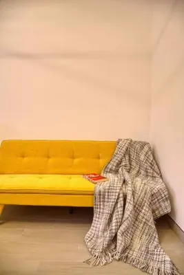 a yellow bench with a blanket on it in a room at The Smart Concierge - Luma 21 in Dubai