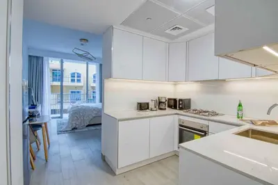 a kitchen with white cabinets and a bed in a room at The Smart Concierge - Luma 21 in Dubai