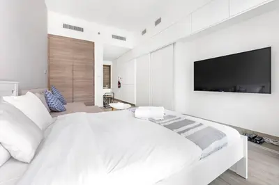 a white bedroom with a large bed and a flat screen tv at StoneTree - Studio One Tower Studio - Amazing View and Facilities in Dubai