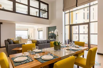 a dining room with a table and yellow chairs at Ain Dubai & Sea Views 2BR Close to Beach, Rimal 4, Jumeirah Beach Residence, by Deluxe Holiday Homes in Dubai