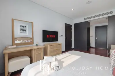 a bedroom with a bed and a desk and a television at LUX The Anantara Residence Suite in Dubai