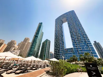 a group of chairs and umbrellas in front of a tall building at Address JBR Marina Views, Address Beach Resort Residence, Dubai Marina - Mint Stay in Dubai