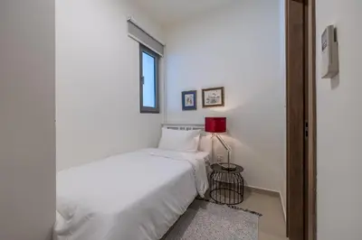 a white bedroom with a bed and a red lamp at Spacious 3BDR Townhouse I Garden I Tilal Al ghaf in Dubai