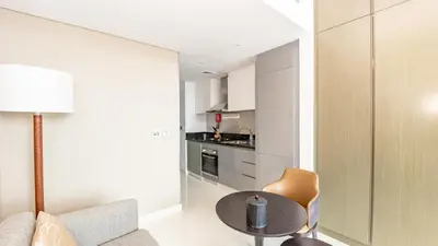 a living room with a table and a kitchen at Sleek Studio in Business Bay with Canal View Business Bay, Dubai in Dubai