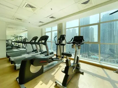 a gym with cardio machines and a large window at Charming 2BR + kid's room w/ Marina yacht view in Dubai