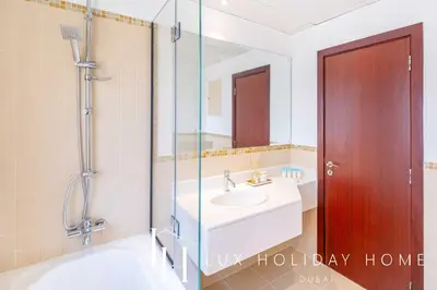 a bathroom with a sink and a shower and a mirror at LUX The JBR Marina View Suite 2 in Dubai