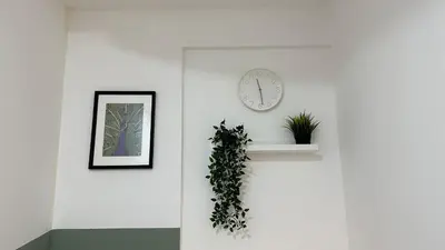 a white wall with a clock and a plant at Beautiful Partition Room in Al barsha 1 Near Metro in Dubai