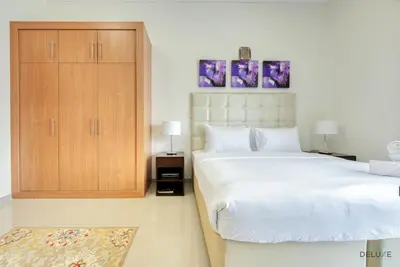 a bedroom with a large bed and a wooden cabinet at Near to Iconic Miracle & Butterfly Garden Urban Vibe Studio, Lincoln Park A, Arjan-Dubailand by Deluxe Holiday Homes in Dubai