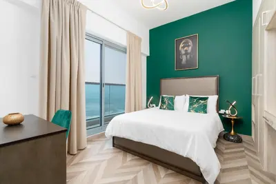 a bedroom with a bed and a green wall at The Elite Apartment in Dubai