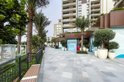 a walkway with palm trees and a building at Luxury apartments at Vida Residences in Dubai