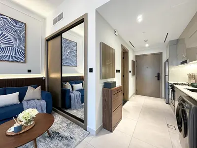 a living room with a blue couch and a table at Trophy - Santorini Studio BurjKhalifa & Canal Views Sofa Bed in Dubai