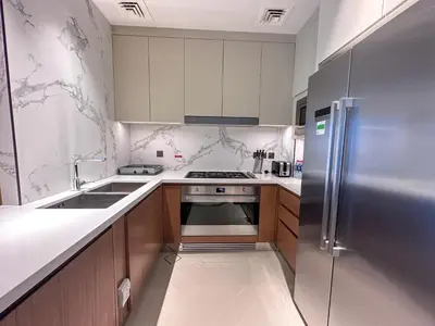 a kitchen with a stainless steel refrigerator and wooden cabinets at Address Residence Dubai Opera 21 by Luxstay Holiday Homes in Dubai