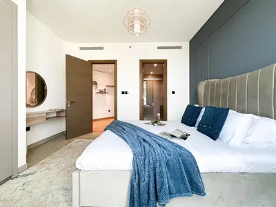 a bedroom with a large white bed with blue pillows at Trophy - Alfresco 2BDR Suite in Dubai