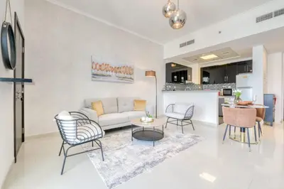 a living room with a couch and chairs and a kitchen at Spacious 1BR in Botanica tower with sea view by PK holidays in Dubai