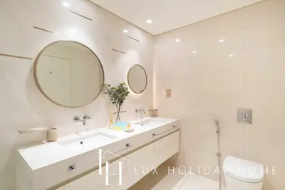 a white bathroom with a sink and a mirror at LUX The Beachfront Island View Suite in Dubai