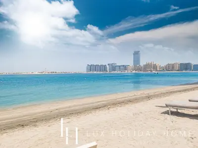 a beach with a bench and a city in the background at LUX The Beachfront Island View Suite in Dubai