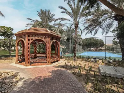 a wooden gazebo next to a swimming pool at Lake Apartments - 1BR Apartment - Allsopp&Allsopp in Dubai