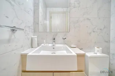 a white bathroom with a sink and a toilet at Serene 1BR at Afnan 3 Midtown Dubai Production City by Deluxe Holiday Homes in Dubai