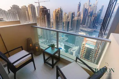 a balcony with chairs and a table and a view of a city at The Refined in Dubai