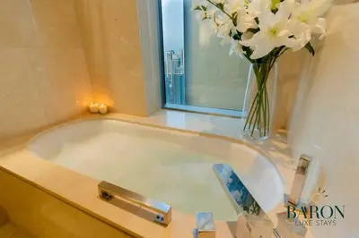 a bath tub with a vase of flowers next to a window at The Refined in Dubai