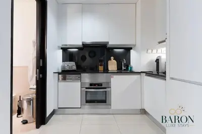a kitchen with white cabinets and stainless steel appliances at The Urban in Dubai