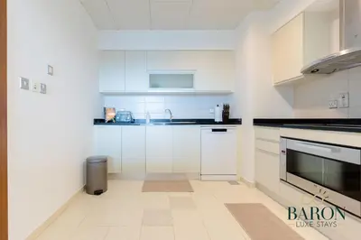a white kitchen with white cabinets and appliances at The Grand Palm Suite Oceana in Dubai