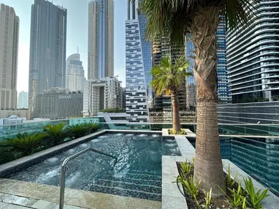 a swimming pool with a palm tree in a city at Lux BnB Upper Crest Tower I Skyline Views in Dubai
